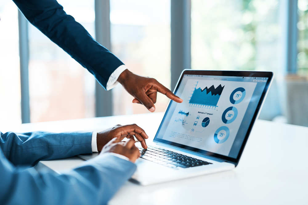 Zwei Personen analysieren Daten und Business Reports auf einem Laptop im Rahmen einer Marketingstrategie bei Docmedicus IT